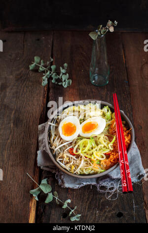 Bol de soupe de nouilles Udon sans gluten avec des carottes, chou chinois, germes de haricots mungo, zoodles et oeuf dur Banque D'Images