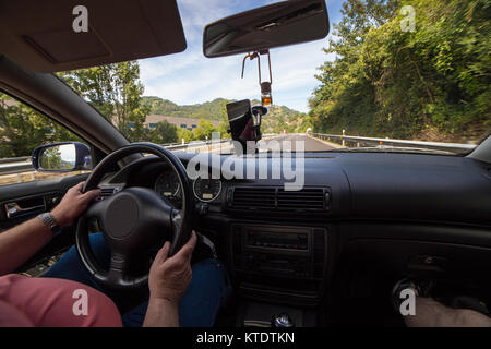 Méconnaissable récolte senior man driving car sur la route d'asphalte dans les montagnes. Banque D'Images