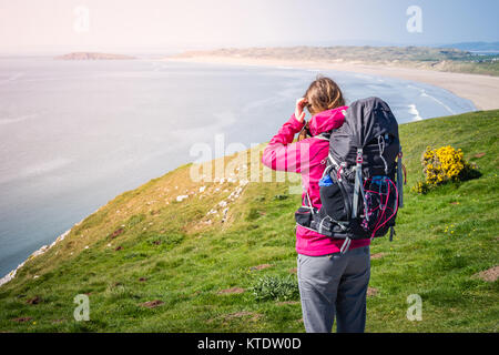 Jeune femme à la recherche de la distance d'une falaise sur la mer dans la côte du Pays de Galles, Rhossili Path Banque D'Images