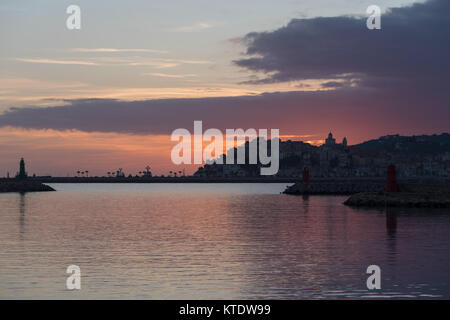 Les nuages colorés spectaculaires au coucher du soleil avec cityscape silhouette. Imperia, Italie Banque D'Images