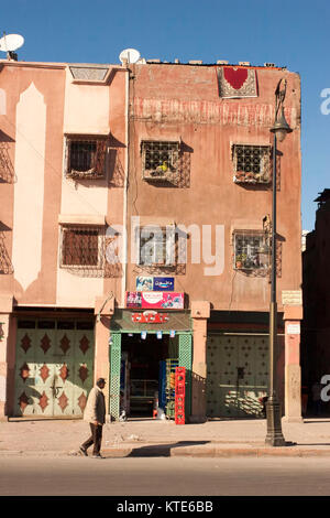 Homme marchant en face des appartements, Marrakech, Maroc Banque D'Images