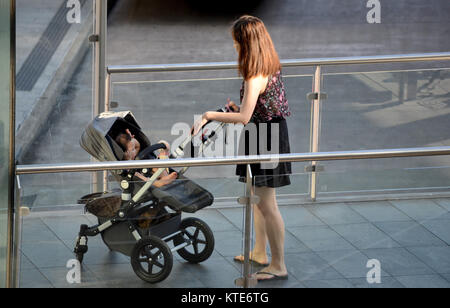 Jeune mère de famille dans la pram à la station de bus Banque D'Images