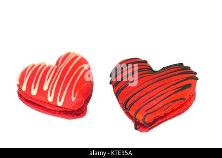 Les macarons en forme de cœur de la Saint-Valentin arrosé de chocolat, sur fond blanc Banque D'Images