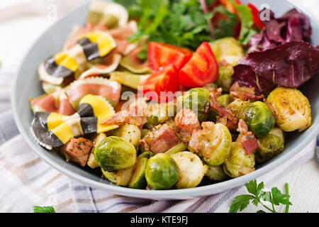 Bol avec pâtes farfalle, choux de Bruxelles aux lardons et salade de légumes frais Banque D'Images