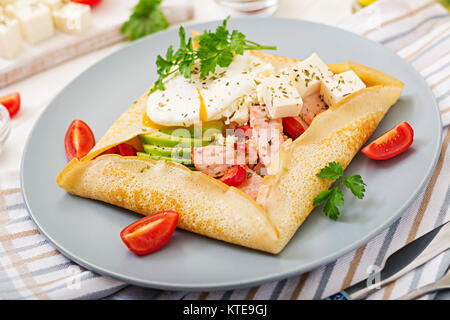 La cuisine française. Le petit-déjeuner, déjeuner et collations. Des crêpes avec oeuf poché, fromage feta, poêlée de jambon, d'avocat et de tomates sur tableau blanc Banque D'Images