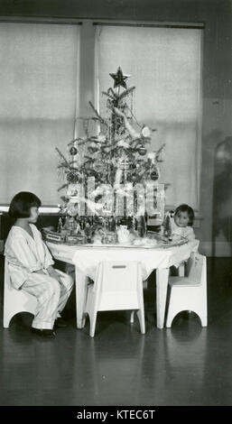 Les enfants sur la réserve indienne de Rosebud, dans le Dakota du Sud s'asseoir à une table qui contient un arbre de Noël avec un petit train qui encirlces. Banque D'Images