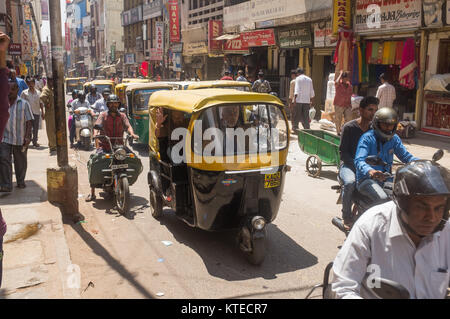 Auto rickshaw et des véhicules se déplaçant sur la rue animée, les gens marcher sur la chaussée à Bangalore, Bangalore, Karnataka, Inde, Asie. Banque D'Images