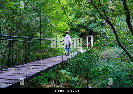 Une femme marche sur un pont suspendu sur la rivière dors. Mañon, province de La Corogne, Galice, Espagne, Europe Banque D'Images