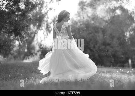 La mariée dans une robe longue est en train de tourner dans l'allée dans le parc un jour d'été Banque D'Images