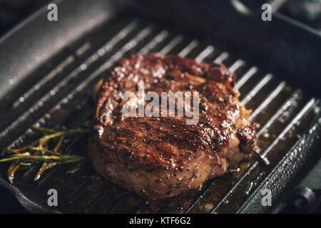 Bifteck de faux-filet de cuisson avec des herbes sur le gril Banque D'Images