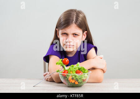 Petite fille est malheureuse car elle n'aime pas manger de la salade. Banque D'Images