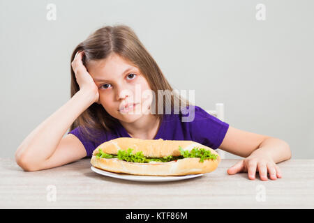 Petite fille est malheureuse car elle doit manger sandwich pour le petit-déjeuner. Banque D'Images