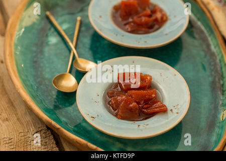 Confiture de Coing en petites plaques placées dans une plaque en céramique turquoise et deux petites cuillères d'or. Tourné avec une faible profondeur de champ Banque D'Images