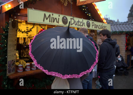 Pluie et vent saluer la dernière minute la veille de Noël Noël les visiteurs de la ville dans le fayre George Square. Décoration grand parapluie mini crêpes néerlandaises Banque D'Images