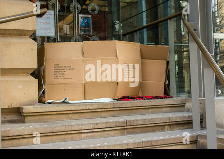 Manchester UK ; 25. Décembre 2017 : les habitants de la rue de Manchester à Manchester le jour de Noël. Deux habitants de la rue placez un morceau de carton à travers une porte de St Anne's Square dans le centre-ville de Manchester de la vie privée et a déclaré qu'ils s'apprêtaient à visiter la vieille Nags Head à prendre jusqu'aux titulaires d'une offre gratuitement un dîner de Noël. Des dizaines de sans-abri de la rue passer Noël Jour recroquevillé dans shop les portes. Crédit : Dave Ellison/Alamy Live News Banque D'Images