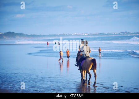 Les gens d'une circonscription chevaux sur la plage de Bali au coucher du soleil , Indonésie Banque D'Images