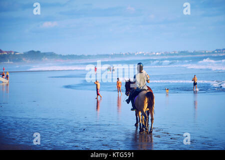 Les gens d'une circonscription chevaux sur la plage de Bali au coucher du soleil , Indonésie Banque D'Images