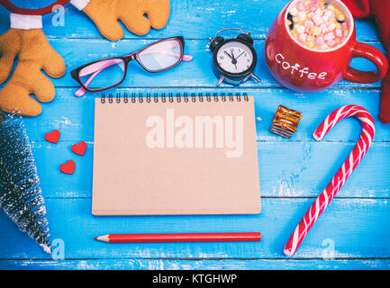 Un ordinateur portable avec des pages vides et marron chocolat chaud dans une tasse en céramique rouge sur une table en bois bleu, vue du dessus Banque D'Images