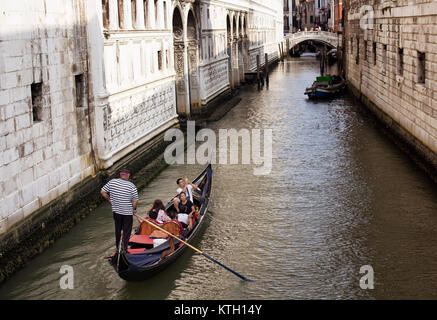 Groupe de touristes asiatiques équitation tour en gondole sur le canal entre les anciens, des bâtiments historiques à Venise / Italie. Banque D'Images