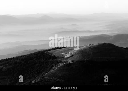 Belle vue aérienne de la montagne Subasio (Assise, Ombrie) au coucher du soleil, avec de longues ombres et une mer de brume remplissant la vallée ci-dessous Banque D'Images