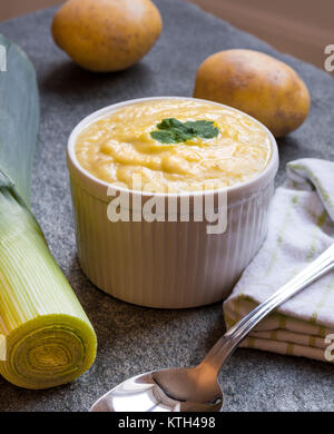 Chaudrée de pommes de terre dans un bol de soupe de poireaux cuisine sur table en pierre entouré par des ingrédients frais Banque D'Images