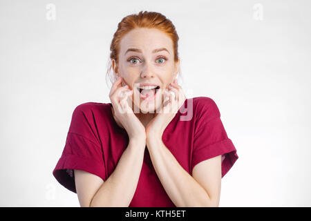 Surpris redhead femme en chemise rouge sur fond blanc Banque D'Images