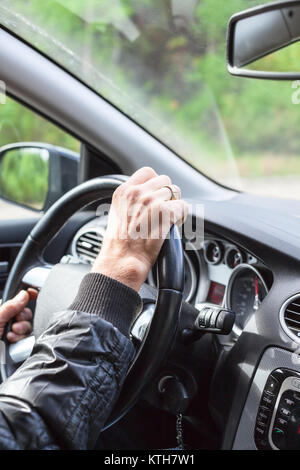 Le conducteur conduit la voiture, close-up view at arms sur volant Banque D'Images