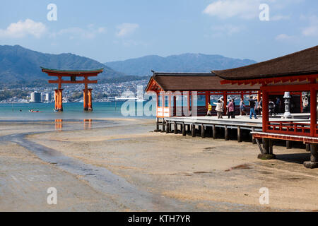 Le Japon, d'Itsukushima-CIRCA avr 2013 : Orange bâtiments en bois d'Itsukushima sont sur la côte ouest de l'île de Miyajima et flottante grand Torii est en ba Banque D'Images