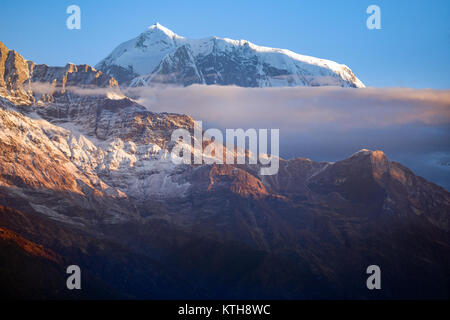 Bord de la chaîne de montagnes de l'Annapurna s'élève au-dessus des nuages et derrière la pente de parois de la montagne. Banque D'Images