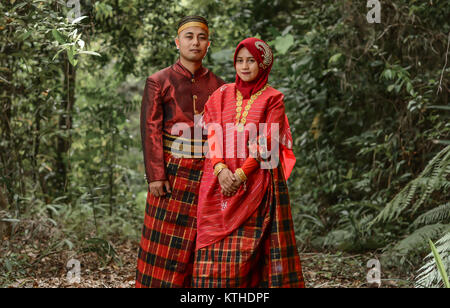 Un jeune couple pose en robe traditionnelle Bugis. Banque D'Images