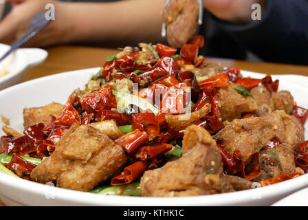 Motion de personnes mangeant du poulet frit épicé chaud sur table à l'intérieur restaurant chinois Banque D'Images