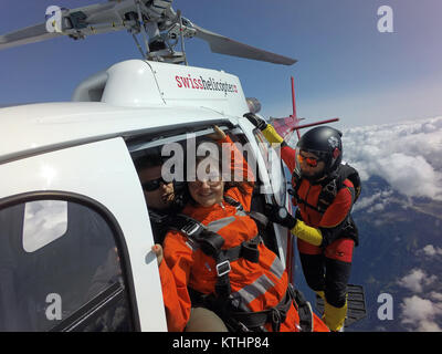 Cette équipe skydiving tandem est l'escalade à l'extérieur de l'hélicoptère et s'apprête à plonger dans l'incertitude de la chute libre. Quelle est la prochaine étape ? Banque D'Images