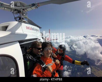 Cette équipe skydiving tandem est l'escalade à l'extérieur de l'hélicoptère et s'apprête à plonger dans l'incertitude de la chute libre. Quelle est la prochaine étape ? Banque D'Images