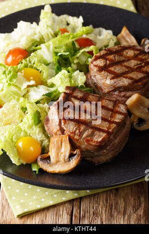 Filet mignon de boeuf avec une salade de chou nappa et les tomates et les champignons sur une plaque sur une table verticale. Banque D'Images