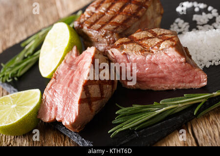 Filet mignon de boeuf fraîchement préparé close-up en tranches sur une planche à découper sur une table horizontale. Banque D'Images