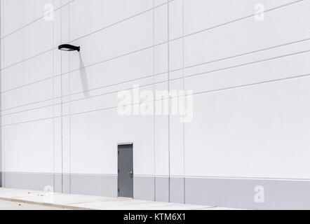 Nouvelle construction de murs blancs d'entrepôt porte noire en métal gris luminaire Banque D'Images