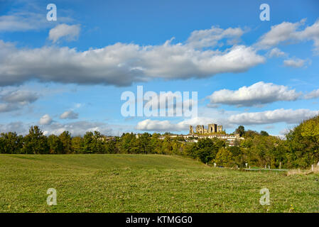 Paysage vert avec arbres d'une distance devant les ruines d'un château médiéval sous un ciel bleu avec des nuages blancs Banque D'Images