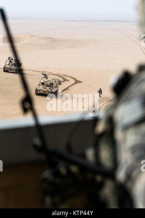 Deux M109A6 Paladin obusiers automoteur exploité par 3e Bataillon du 16e Régiment d'artillerie, 2ème Armored Brigade Combat Team, 4e Division d'infanterie, en tout en navigant de première classe Ian Patterson, un contrôleur aérien tactique de l'Armée de l'air Spécialiste de la partie 82e Escadron expéditionnaire Opération de soutien aérien, appel dans le feu de l'Armée deux AH-64 Apaches, exploité par 4e bataillon du 227e Bataillon de Reconnaissance, d'attaque, 1e de cavalerie, maintenant sous la 42e Brigade d'aviation de combat, au cours d'une mission de formation mixte le 15 janvier 2014, quelque part dans le sud-ouest de l'Asie. La 42e armée de la cabine, New York Nationa Banque D'Images