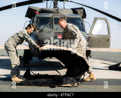 Le capitaine Mindy Wallace et l'Adjudant-chef Toleman Miller, tous deux à partir de la 3e bataillon du 238e bataillon de l'aviation d'appui général, Michigan Army National Guard, rabattre le couvercle d'un UH-60 Blackhawk tout en se préparant à un vol le 6 février 2014, au Camp Buehring, le Koweït. Les soldats du bataillon, en vertu de la 42e Brigade d'aviation de combat, la Garde Nationale de New York, a récemment déployé au Koweït en provenance des États-Unis et d'exploiter les Blackhawks dans la région dans le cadre de l'opération Enduring Freedom. (New York) La Garde nationale de l'armée photo par le Sgt. Harley Jelis/libérés) Banque D'Images