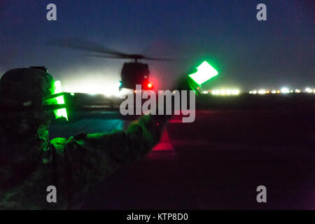 Le Sgt. Joann Duclose de première classe, un conseiller principal en ressources humaines de la Sergent 642e Bataillon de soutien à l'aviation, les gestes à un UH-60 Black Hawk de se soulever pendant la nuit charge sous élingue avec formation d'aviateurs du 3 e Bataillon, 142e Bataillon d'hélicoptères d'assaut, le 5 juin 2014, au Camp Buehring, le Koweït. La 642e et 142e, tant dans le cadre de la 42e Brigade d'aviation de combat, la Garde Nationale de New York, sont déployés au Koweït dans le cadre de l'opération Enduring Freedom. (New York) La Garde nationale de l'armée photo par le Sgt. Harley Jelis/libérés) Banque D'Images