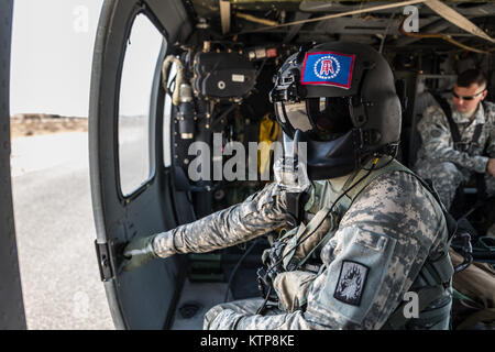 La CPS. Giles Dunlop, chef d'équipe avec l'entreprise C, 1er Bataillon, 214e Air Ambulance, 42e Brigade d'aviation de combat (cabine), surveille son vol's UH-60 Black Hawk comme il se prépare à décoller avant un exercice avec un personnel de l'Armée de l'air koweïtienne hélicoptère Puma SA 330 le 19 juin 2014, au Koweït. 42e CAB et forces koweïtiennes effectuent régulièrement des joint aviation partenariats pour accroître leur capacité à répondre à toute urgence. La 42e CAB, New York, de la Garde nationale de l'armée est déployée au Koweït dans le cadre de l'opération Enduring Freedom. (New York) La Garde nationale de l'armée photo par le Sgt. Harley Jelis/libérés) Banque D'Images