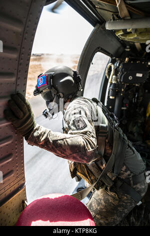 La CPS. Giles Dunlop, chef d'équipe avec l'entreprise C, 1er Bataillon, 214e Air Ambulance, 42e Brigade d'aviation de combat (cabine), vérifie les environs de son UH-60 Black Hawk qu'il le faudra, au cours d'un exercice de récupération du personnel avec une force aérienne koweïtienne hélicoptère Puma SA 330 le 19 juin 2014, au Koweït. 42e CAB et forces koweïtiennes effectuent régulièrement des joint aviation partenariats pour accroître leur capacité à répondre à toute urgence. La 42e CAB, New York, de la Garde nationale de l'armée est déployée au Koweït dans le cadre de l'opération Enduring Freedom. (New York) La Garde nationale de l'armée photo par le Sgt. Harley Jelis/libérés) Banque D'Images