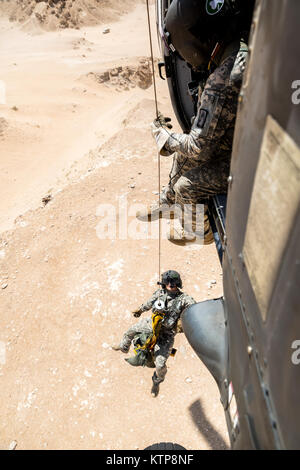 La CPS. Mouyos Nicholas, un médecin de vol, est soulevée par un palan par la CPS. Giles Dunlop, chef d'équipe, avec une simulation de casulaty pendant un exercice de récupération du personnel entre un UH-60 Black Hawk piloté par la société C, 1er Bataillon, 214e Air Ambulance, 42e Brigade d'aviation de combat (cabine), et une Force aérienne koweïtienne hélicoptère Puma SA 330 le 19 juin 2014, au Koweït. 42e CAB et forces koweïtiennes effectuent régulièrement des joint aviation partenariats pour accroître leur capacité à répondre à toute urgence. La 42e CAB, New York, de la Garde nationale de l'armée est déployée au Koweït dans le cadre de l'opération Enduring Freedom. (New York) Banque D'Images