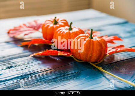 Close up trois citrouilles et feuilles d'érable artificiel bleu sur fond de bois concept d'automne Banque D'Images