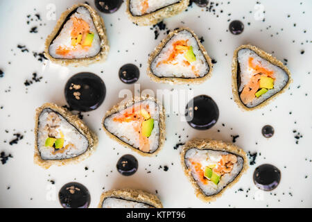 La cuisine japonaise traditionnelle rouleaux de sushi sur fond blanc recouvert de gouttes de sauce Banque D'Images