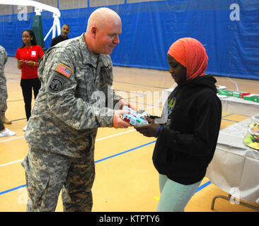 Le major John Fitzpatrick, 369e brigade de maintien en puissance, remet un cadeau à un enfant de l'Harlem Children's Zone durant un jouet et enduire à l'événement d'entraînement Harlem Armory, le 5 décembre 2015. L'événement était organisé comme un moyen pour le 369e brigade de maintien en puissance de donner en retour à la communauté dans laquelle l'unité a ses racines. (US Army National Guard photo par le Sgt. Jeremy Bratt, 369e Brigade de soutien/libérés) Banque D'Images