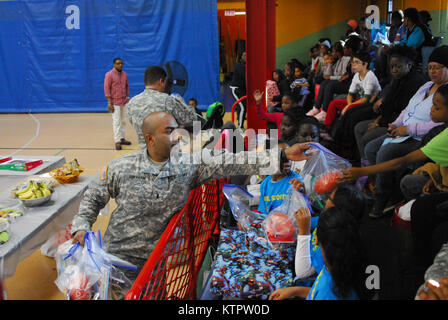 1er lieutenant James Abraham, 369e Brigade de soutien, les mains des cadeaux aux enfants de l'Harlem Children's Zone durant un jouet et enduire à l'événement d'entraînement Harlem Armory, le 5 décembre 2015. L'événement était organisé comme un moyen pour le 369e brigade de maintien en puissance de donner en retour à la communauté dans laquelle l'unité a ses racines. (US Army National Guard photo par le Sgt. Jeremy Bratt, 369e Brigade de soutien/libérés) Banque D'Images