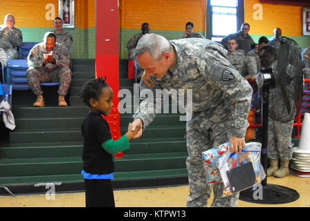 L'Adjudant-chef Gerard Ford, 369e brigade de maintien en puissance, remet un cadeau à un enfant de l'Harlem Children's Zone durant un jouet et enduire à l'événement d'entraînement Harlem Armory, le 5 décembre 2015. L'événement était organisé comme un moyen pour le 369e brigade de maintien en puissance de donner en retour à la communauté dans laquelle l'unité a ses racines. (US Army National Guard photo par le Sgt. Jeremy Bratt, 369e Brigade de soutien/libérés) Banque D'Images