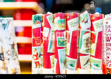 Rouleaux de papier d'emballage de Noël traditionnel emballés sous film rétractable dans des tubes et sur l'affichage dans une fenêtre de magasin de vente au détail au Royaume-Uni Banque D'Images