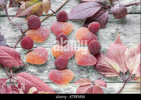 Belle marmelade de fruits en forme de cœur aux fruits rouges framboises mûres fraîches sur l'arrière-plan de feuilles lumineuses colorées. Le Fram horizontale Banque D'Images